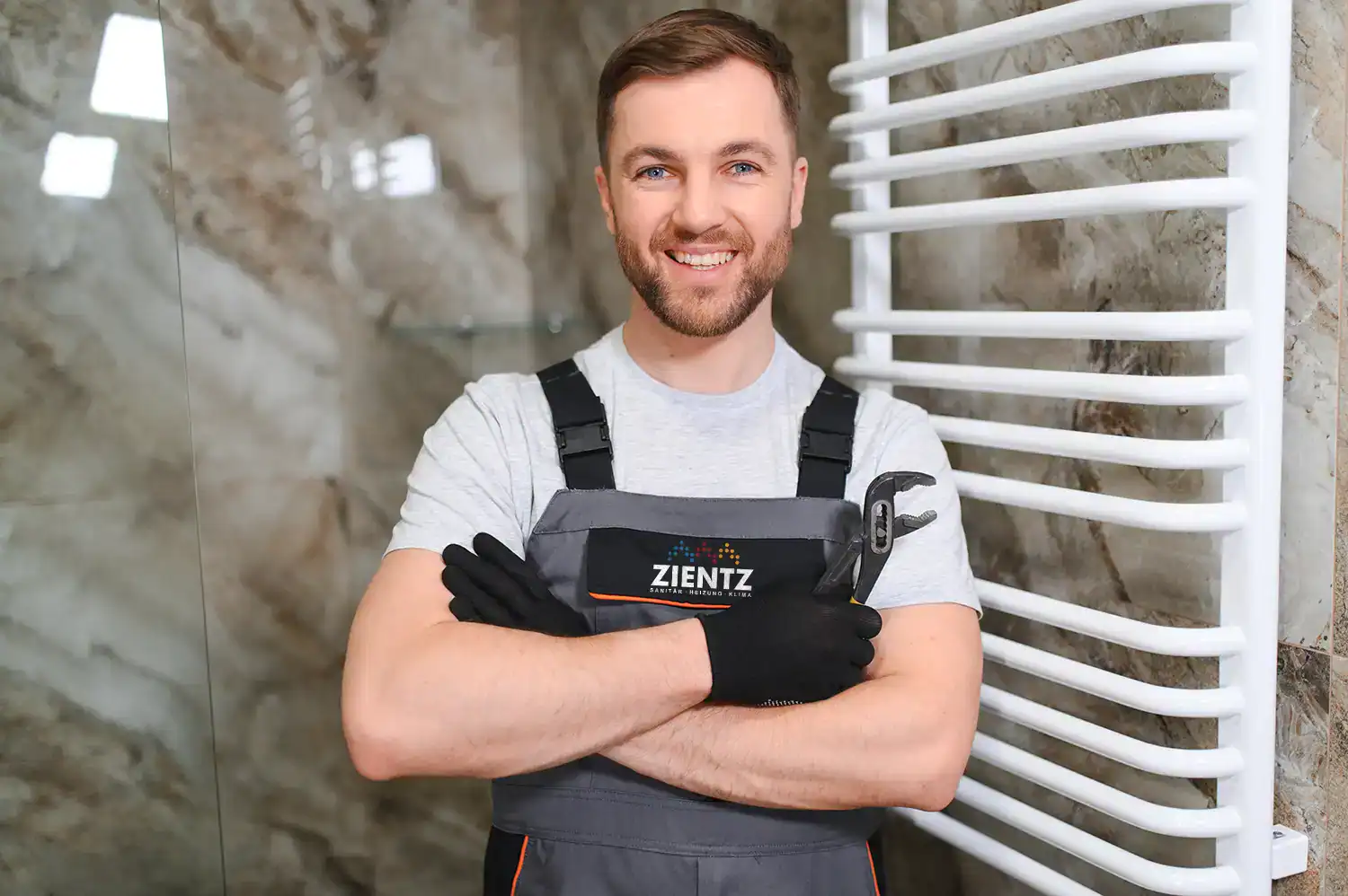 Anlagenmechaniker von SHK Zientz mit Rohrzange in einem modern ausgestatteten Badezimmer