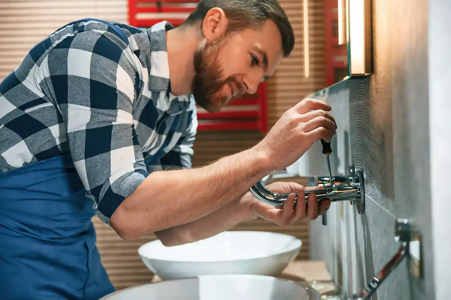 Sanitärinstallateur bei der Wartung einer wandmontierten Waschtischarmatur