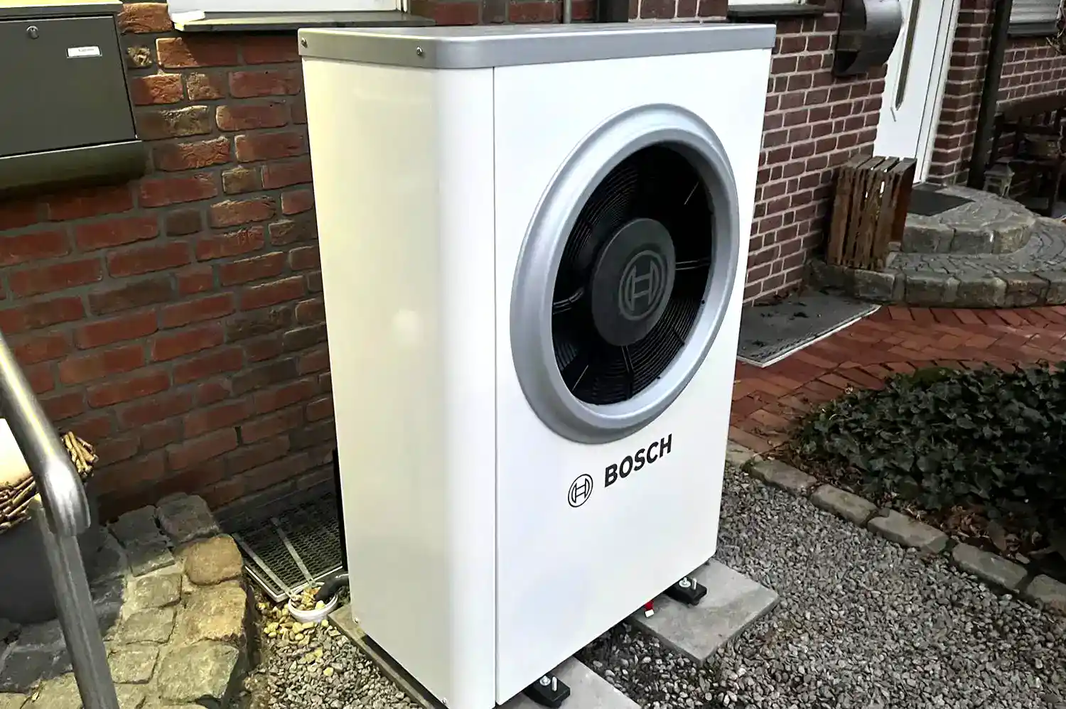 Außeneinheit einer Bosch Wärmepumpe neben einem Wohnhaus